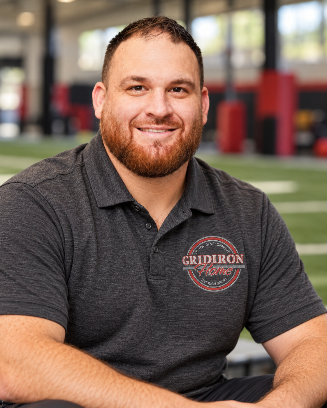 Illustrative portrait of Rob Hamilton wearing a dark gray polo with a subtle Gridiron Home logo at a sports training facility