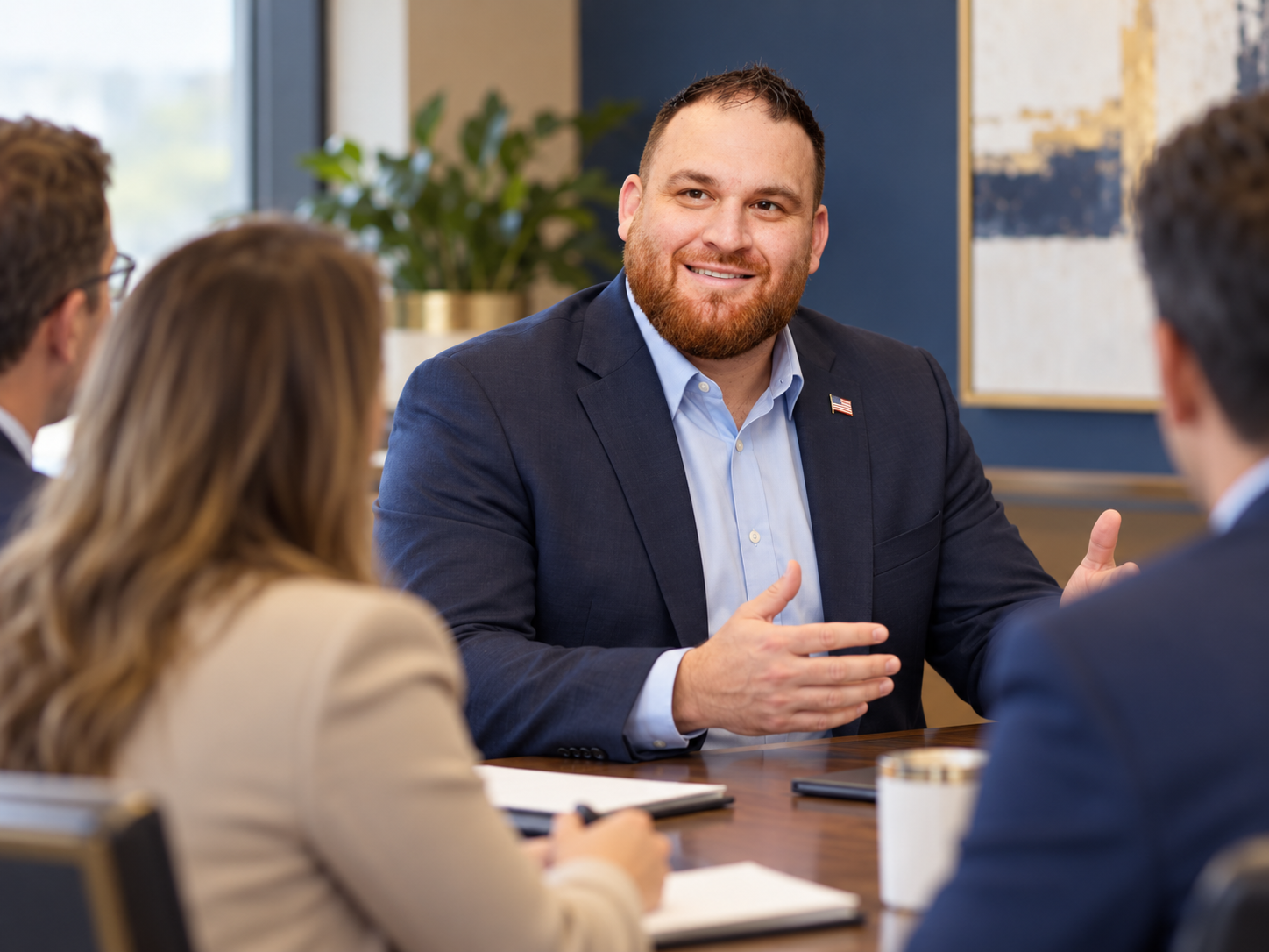 Illustrative portrait of Rob Hamilton in a blue suit with an American flag pin at a meeting